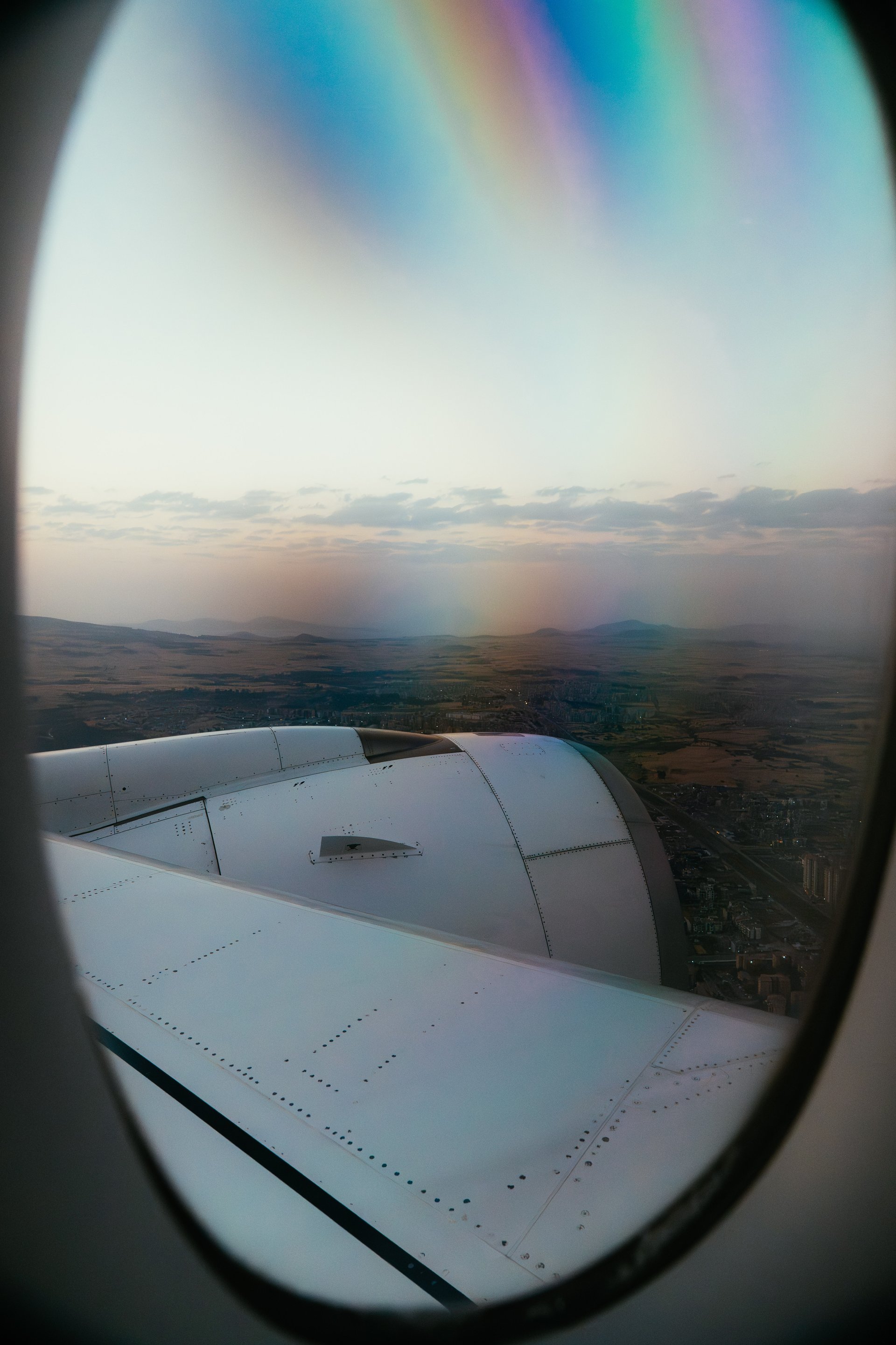 Rainbow Light Through Airplane Window Over Approaching Land