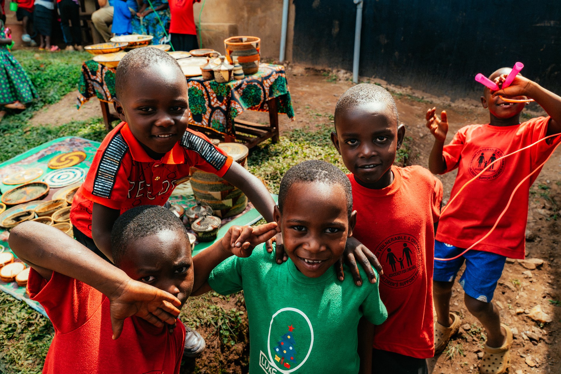 Vier Jungs lachen zusammen auf einem Schulhof in Uganda