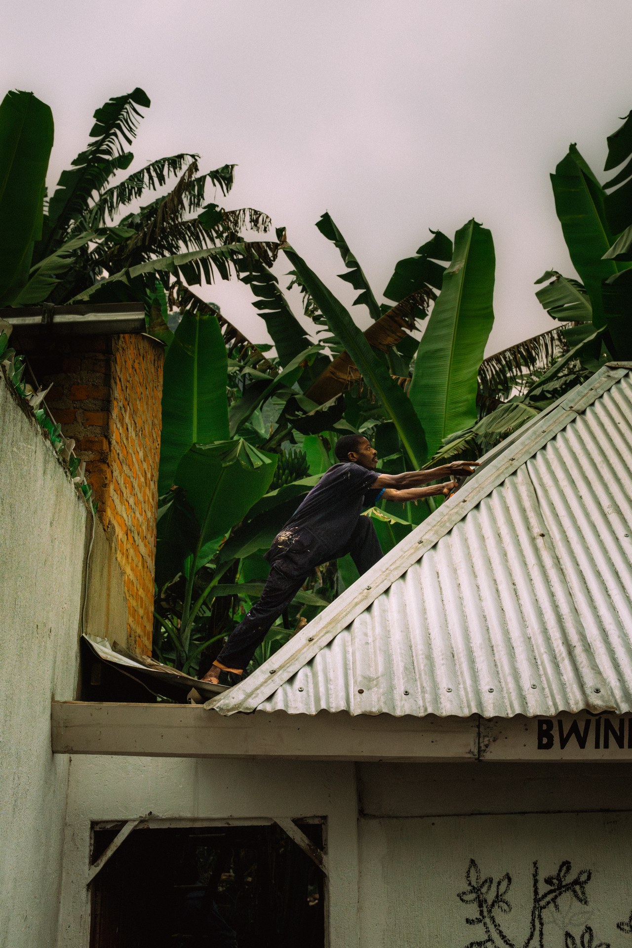 Craftsman repairing roof at Buhoma orphanage