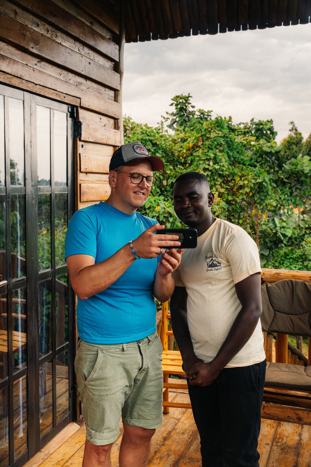 Two men sharing a phone on a highland road in Uganda