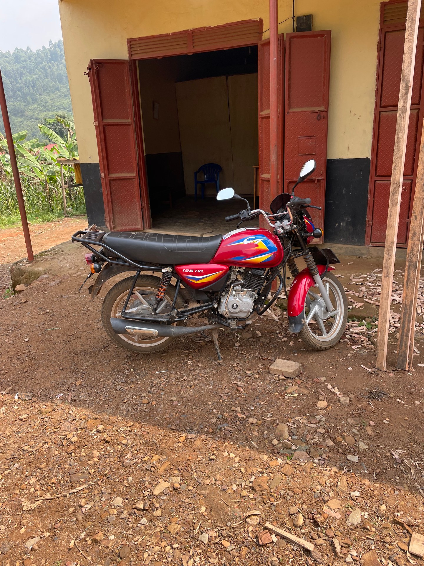 Red motorcycle in front of yellow house in Buhoma