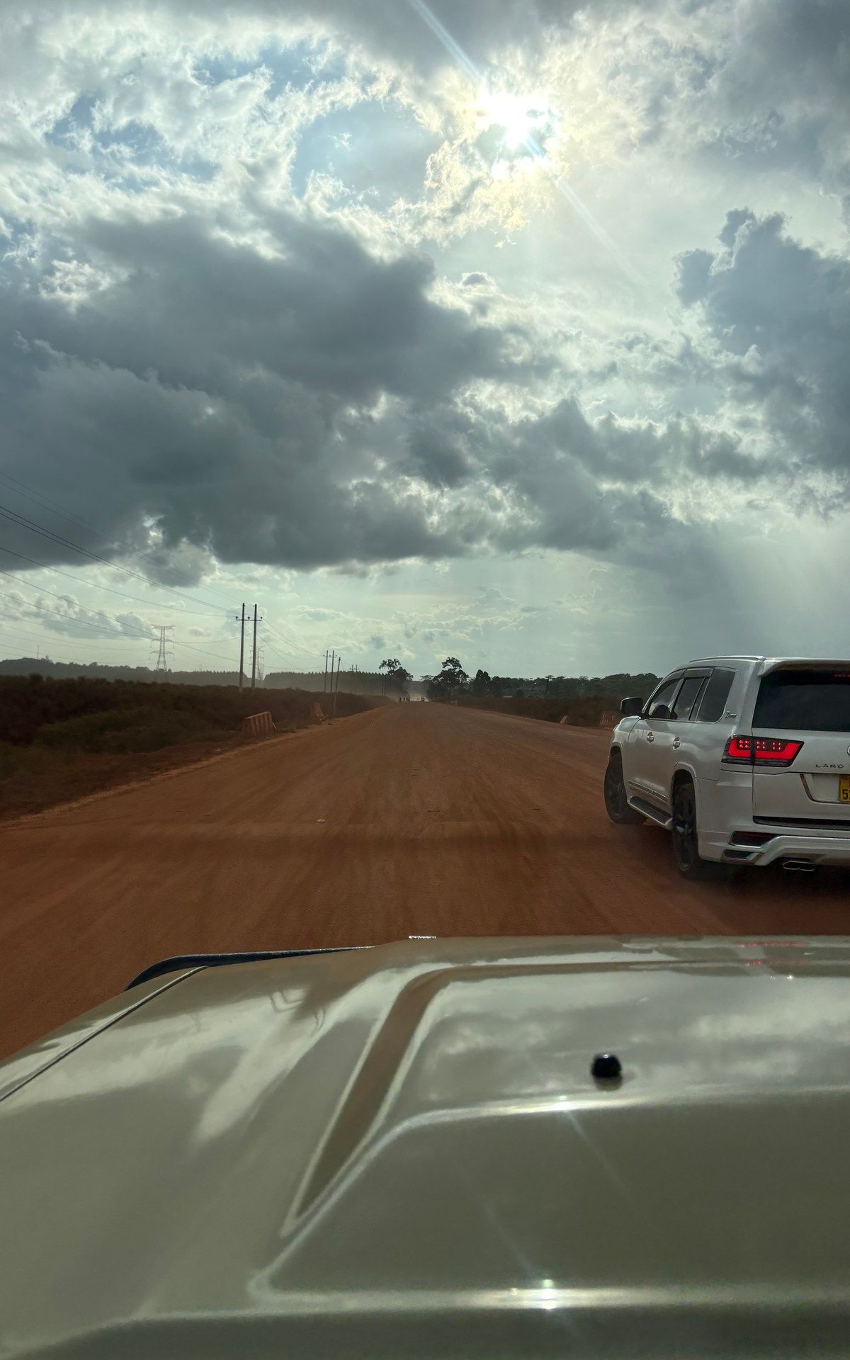 Red laterite road stretching into the Ugandan landscape — photographed on location, January 2026
