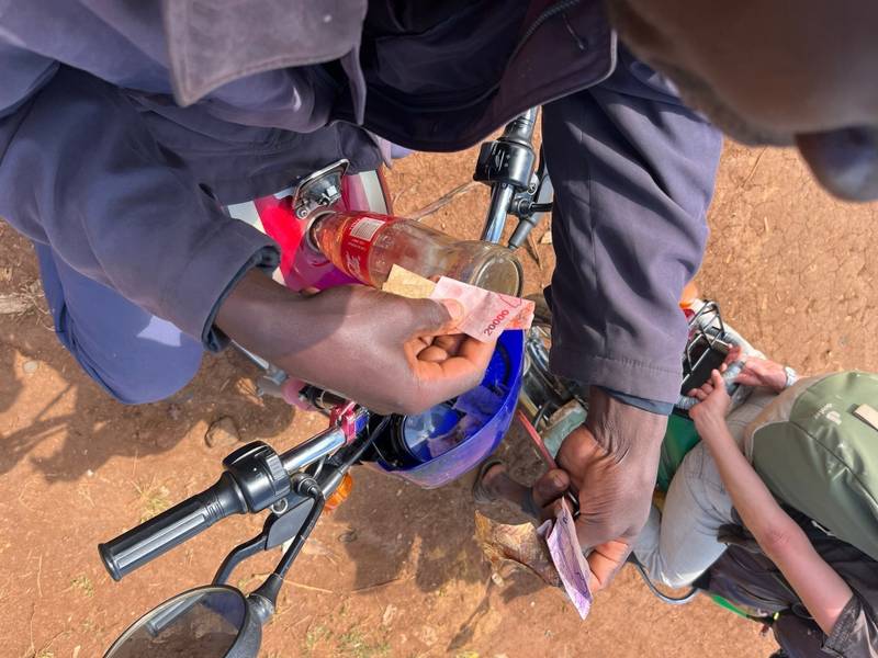 Benzin aus einer Cola-Flasche wird in einen BodaBoda gefüllt