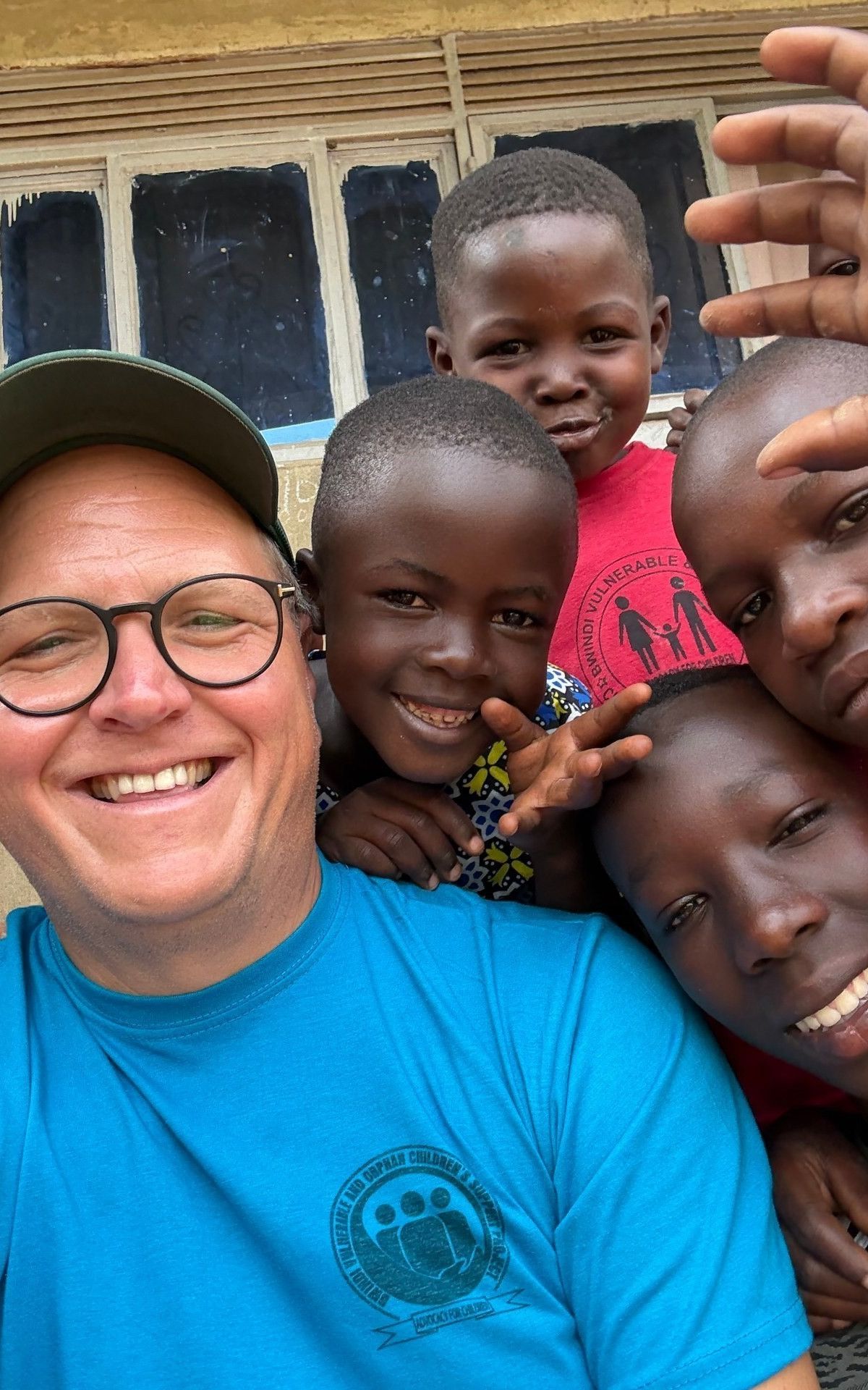 Mark Suer mit Kindern im Waisenhaus Nicholas, Buhoma — Gruppenfoto auf dem Sandplatz, Januar 2026. Foto: Mark Suer