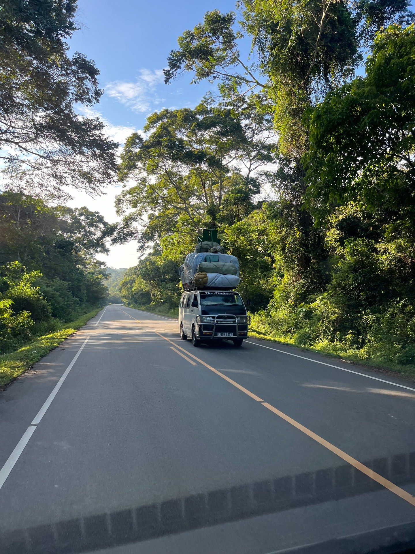 An overloaded minibus transporting mattresses and household goods on the road from Butiru towards Murchison Falls National Park, Uganda, October 2024 — a characteristic sight on Ugandan highways