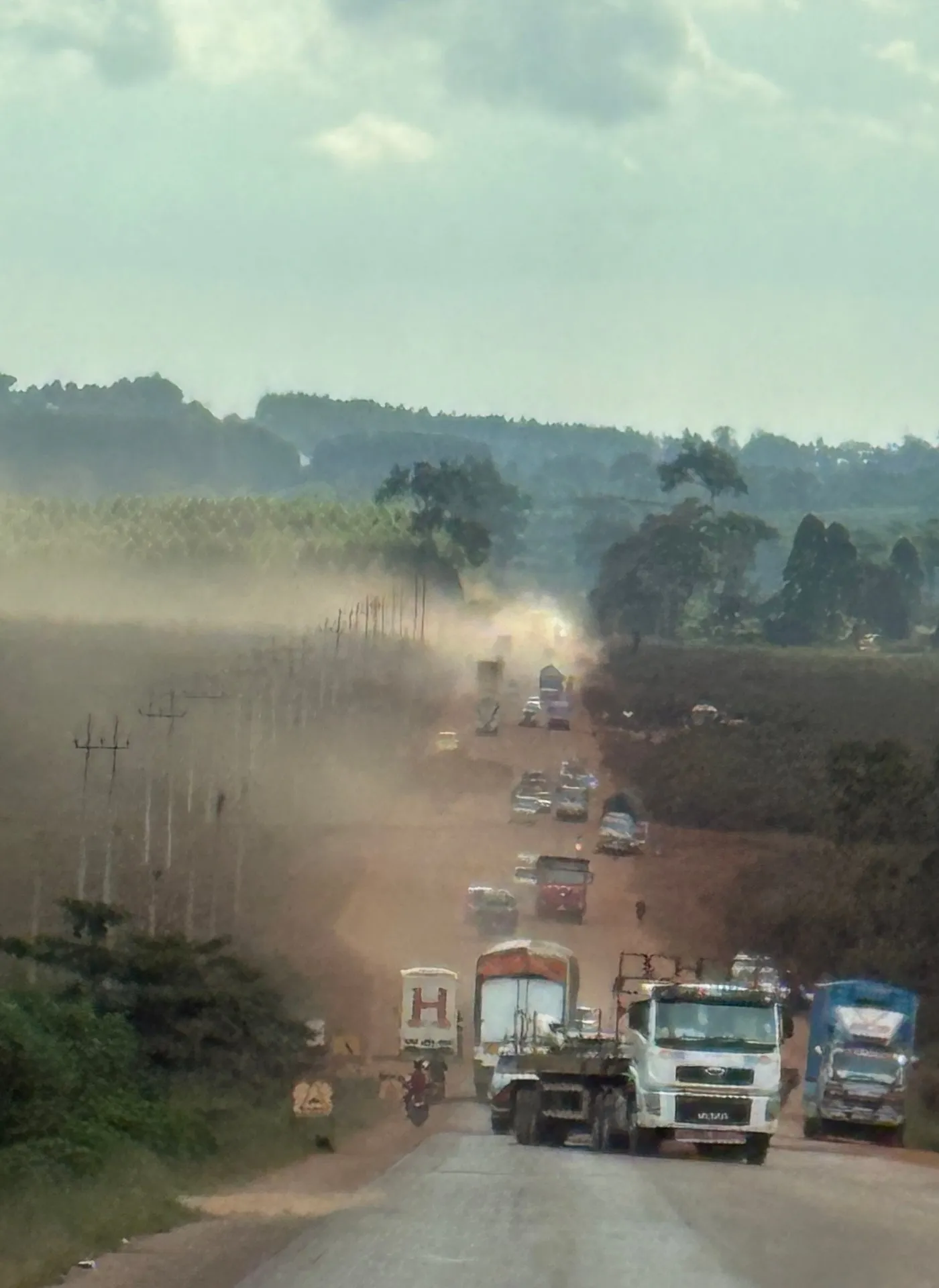 Dusty Masaka Highway with boda-boda motorcyclists and a lorry, Uganda infrastructure. Photo: Mark Suer