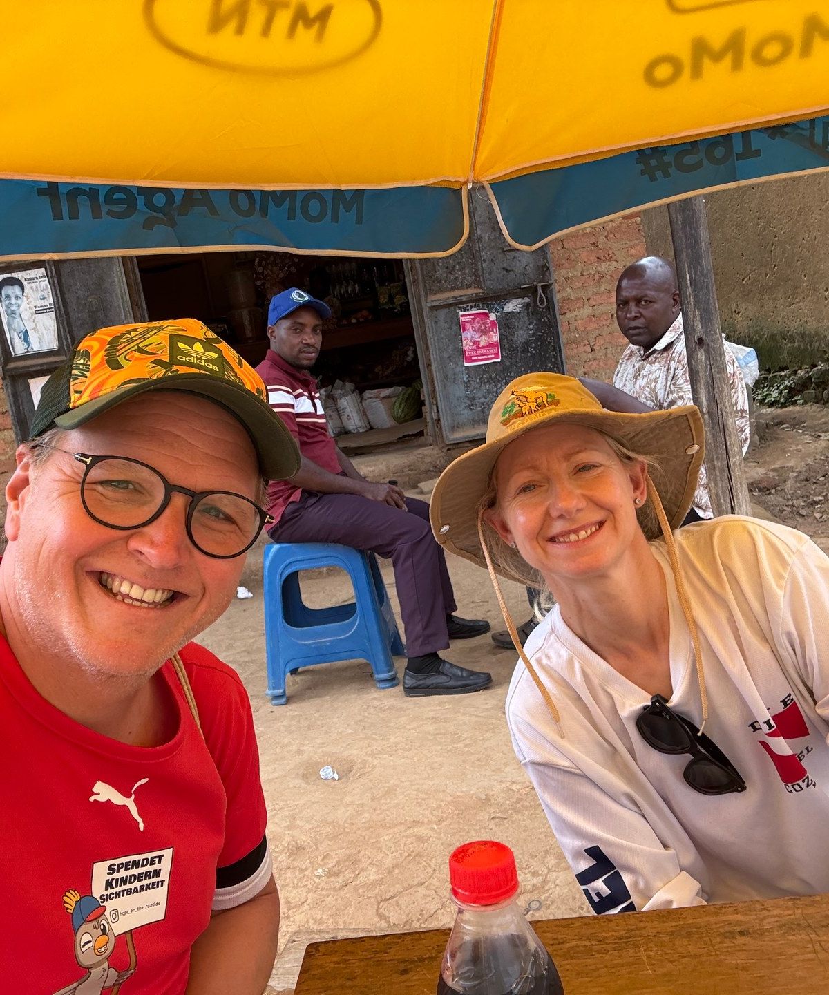 Pause an einem kleinen Laden in Buhoma — Mark Suer und Susanne Suer sitzen auf einer Bank an der Hauptstraße, Juni 2026